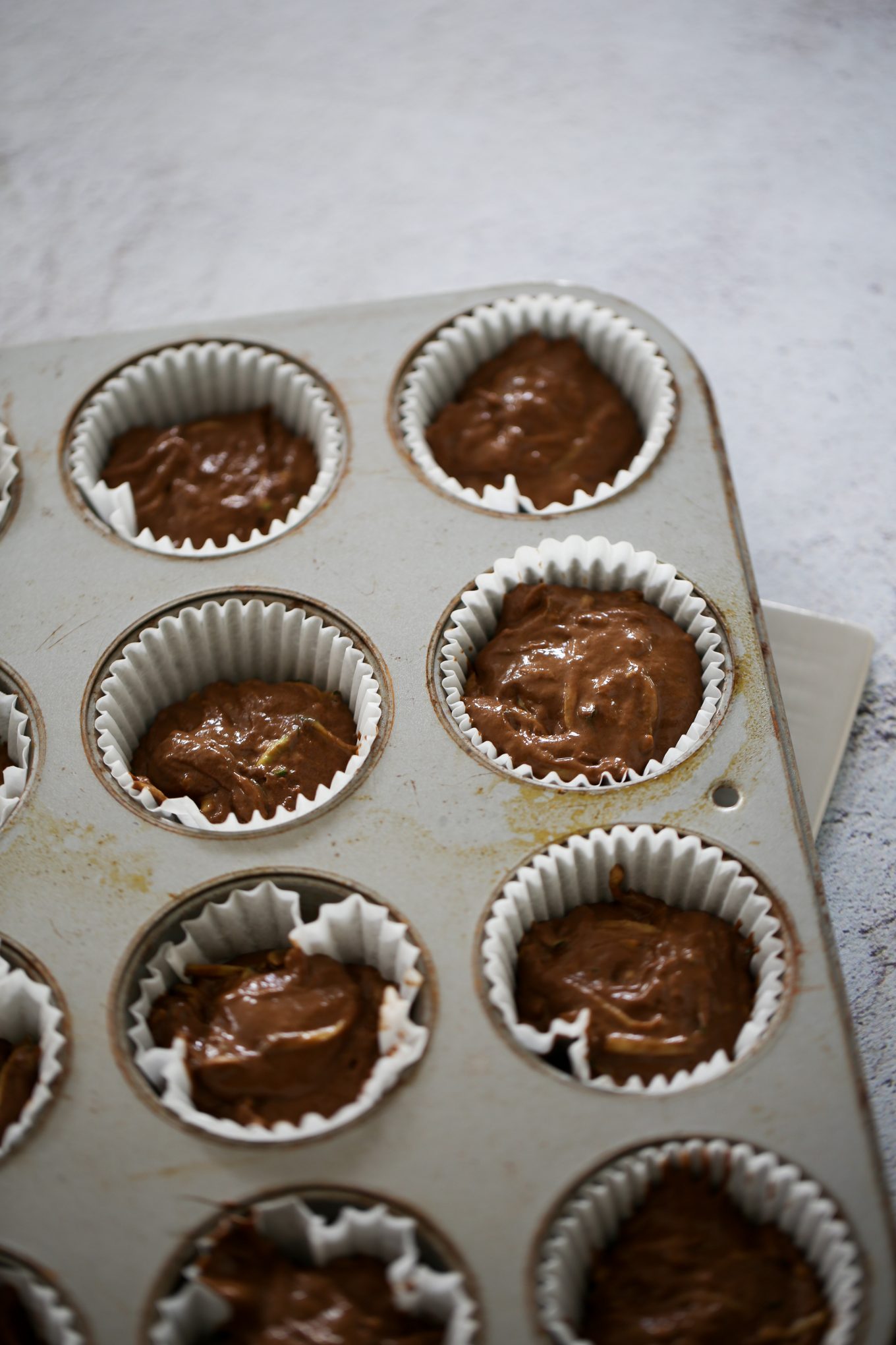 muffins de chocolate y calabacita en una charola para muffins antes de meter al horno