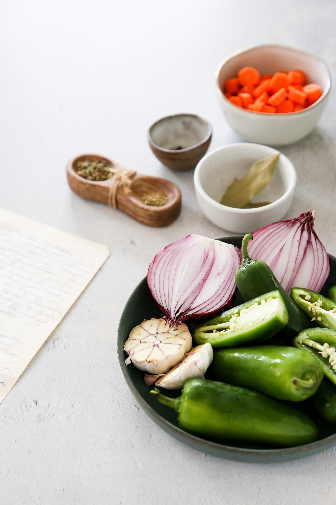 ingredients for making my family pickled jalapeños recipe, sliced jalapeños, red onion, garlic, spices and carrots.