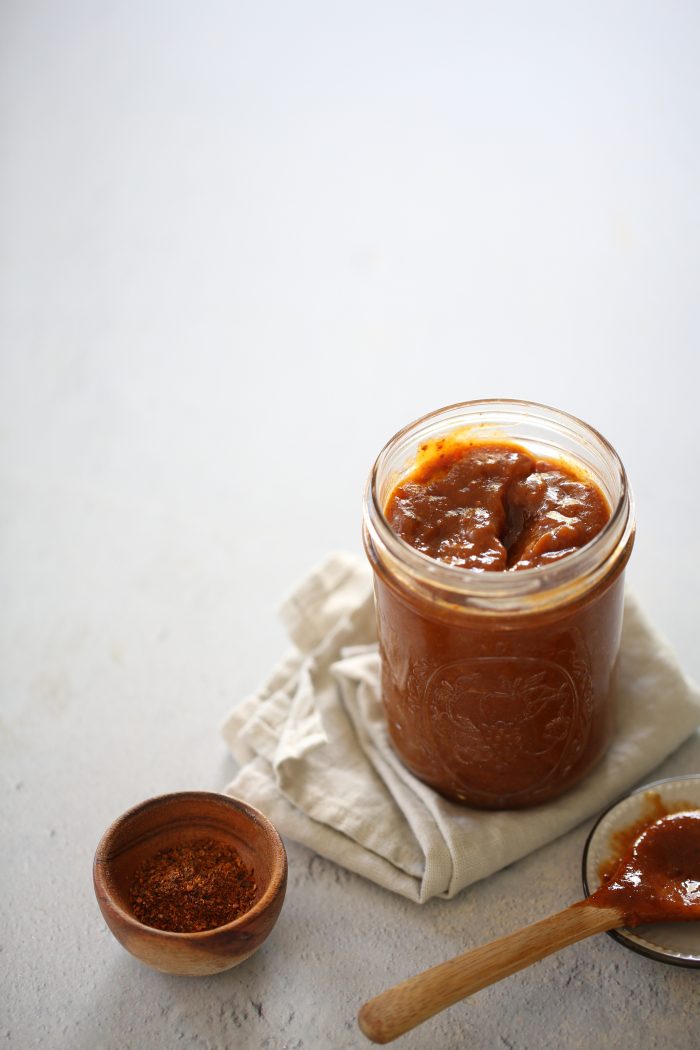 Mexican chamoy (chamoi) in a jar and a tiny bowl of ground chile ancho.
