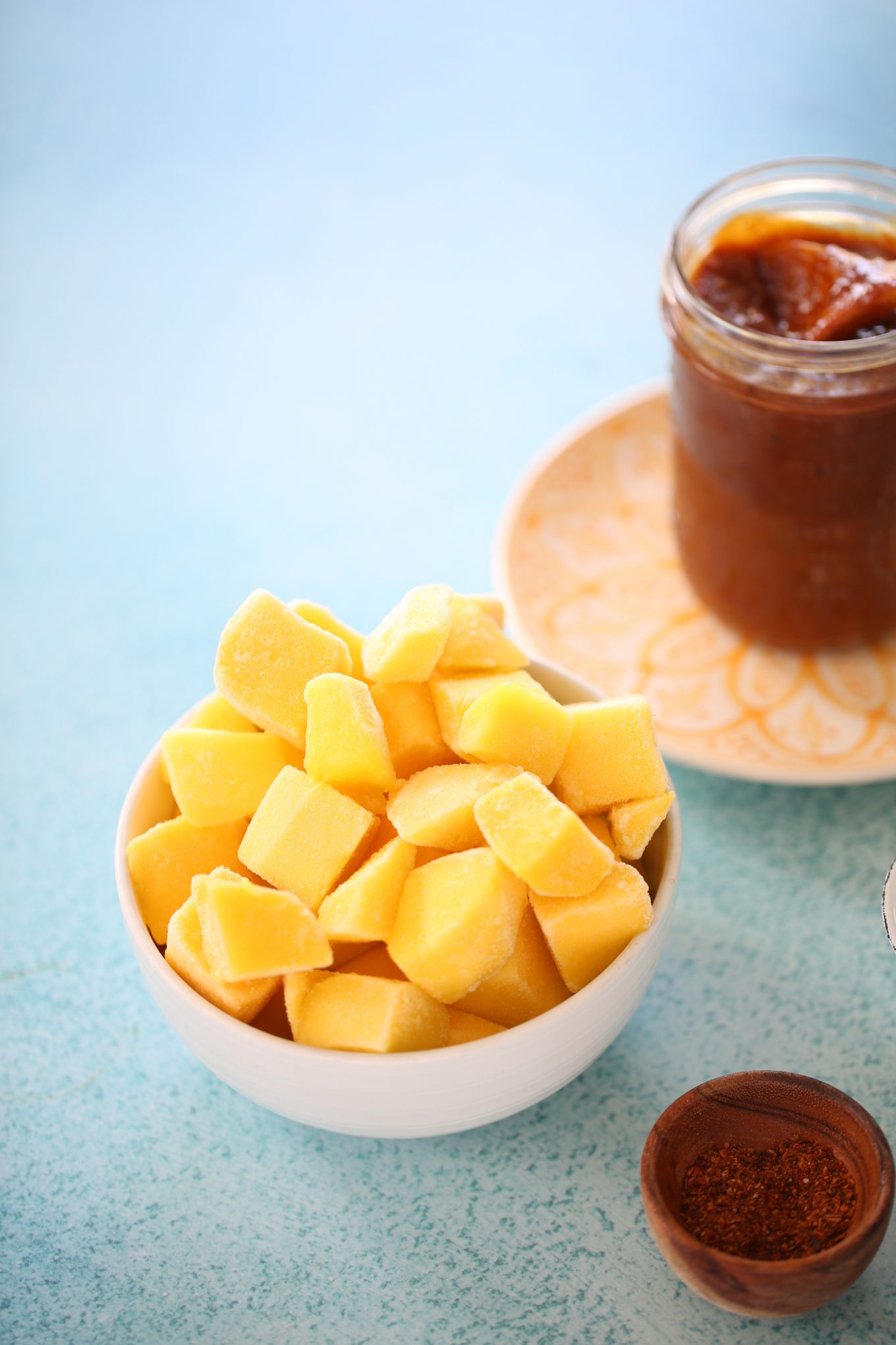 a bowl with fozen mango and a jar of homemade chamoy sauce in the back