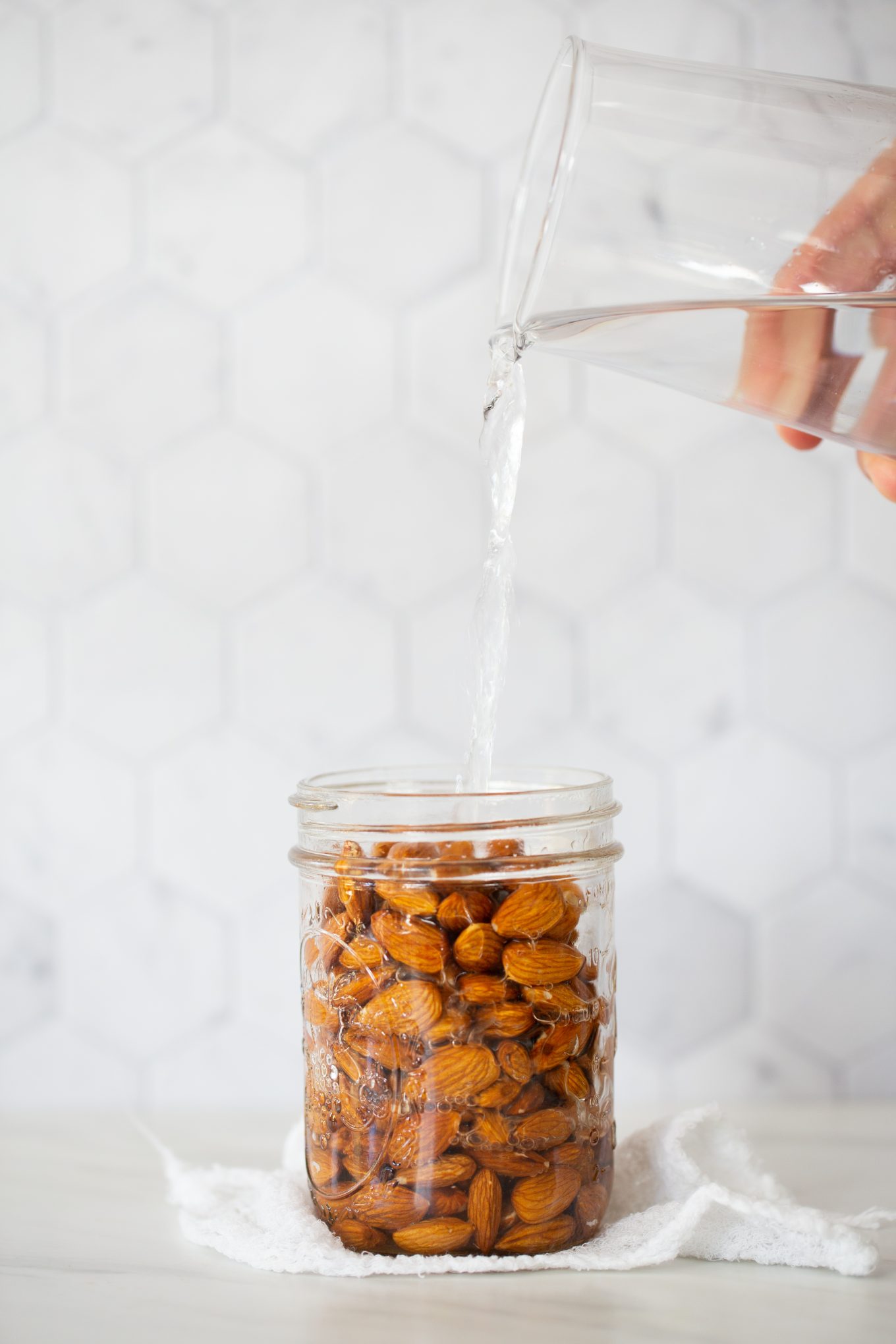 pouring water into a jar with almons