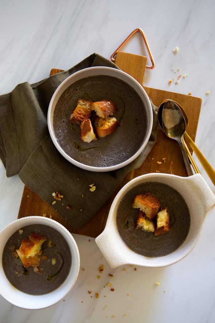 three bowls of vegan cram of  mushroom soup topped with croutons