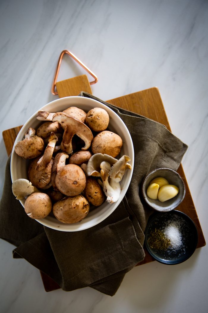 a bowl with different type of mushrooms, garlic and salt ans spices