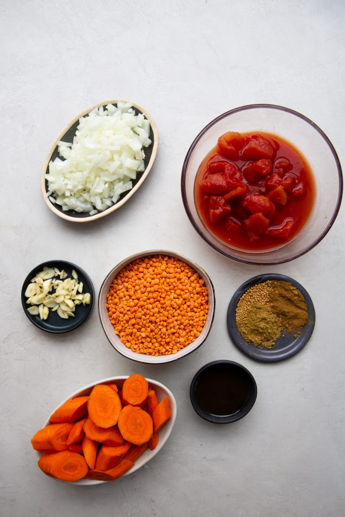 Tomate, cebolla, ajo, lentejas, especias, zanahoria y aceite listos y medidos para hacer la sopa.