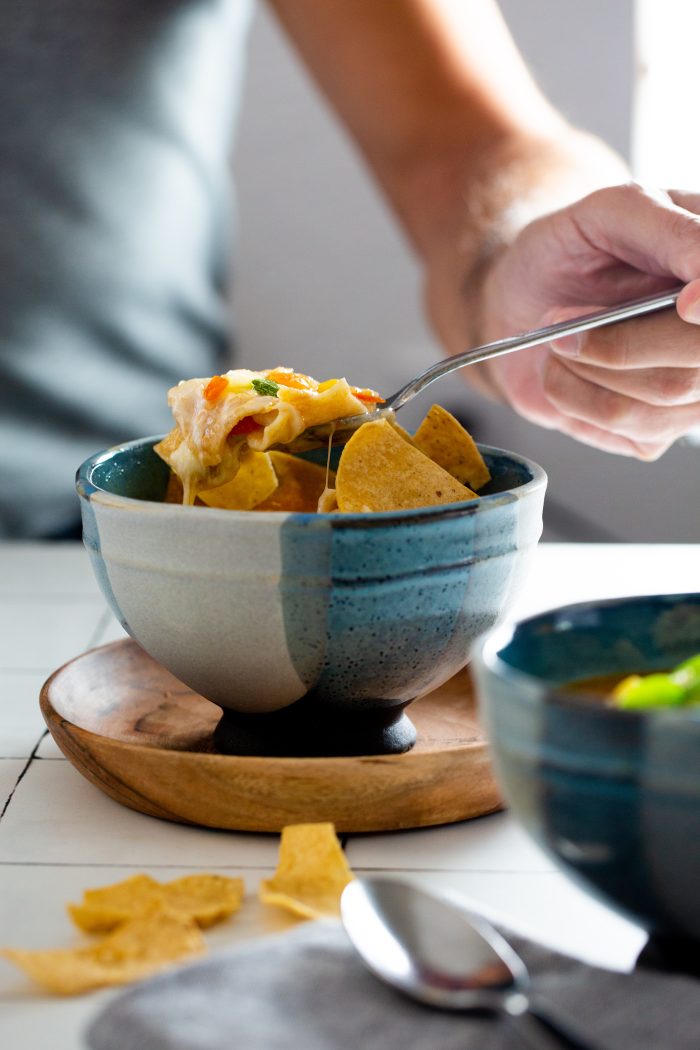 Taking a spoonful of a Mexican vegan calabacitas, corn and tomato soup.