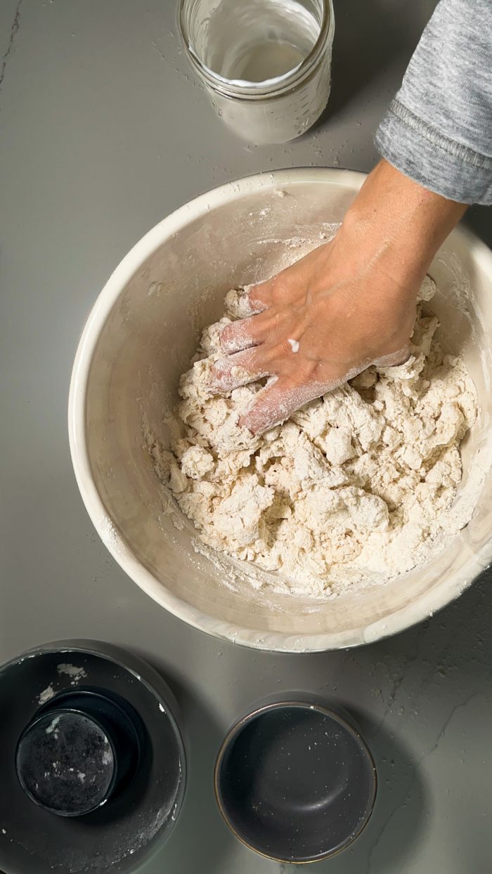 A person kneading dough in a bowl.