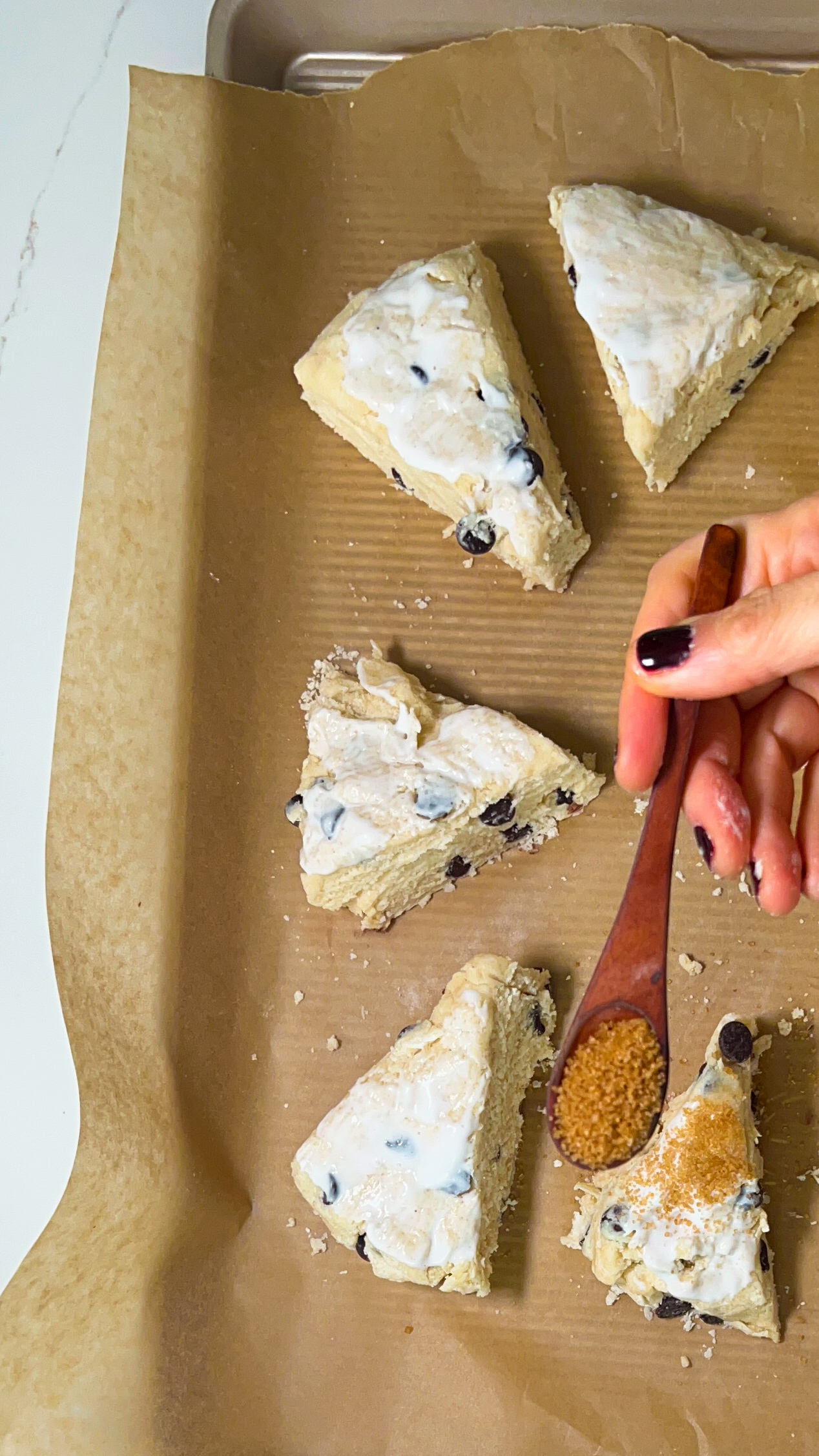 a person putting turbinado suigar ontop of scones