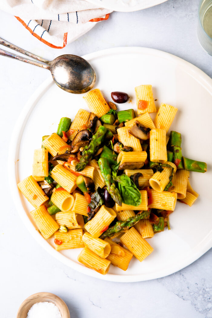 pasta con espárragos y champiñones sobre un plato blanco