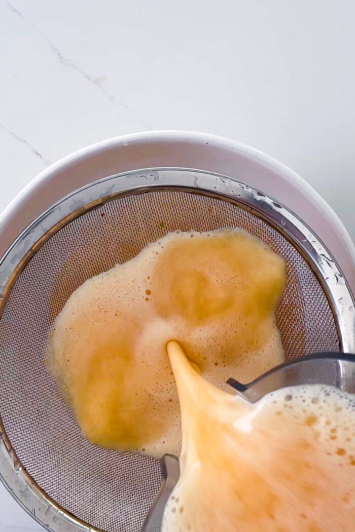strianing the agua de melon through a fin sieve