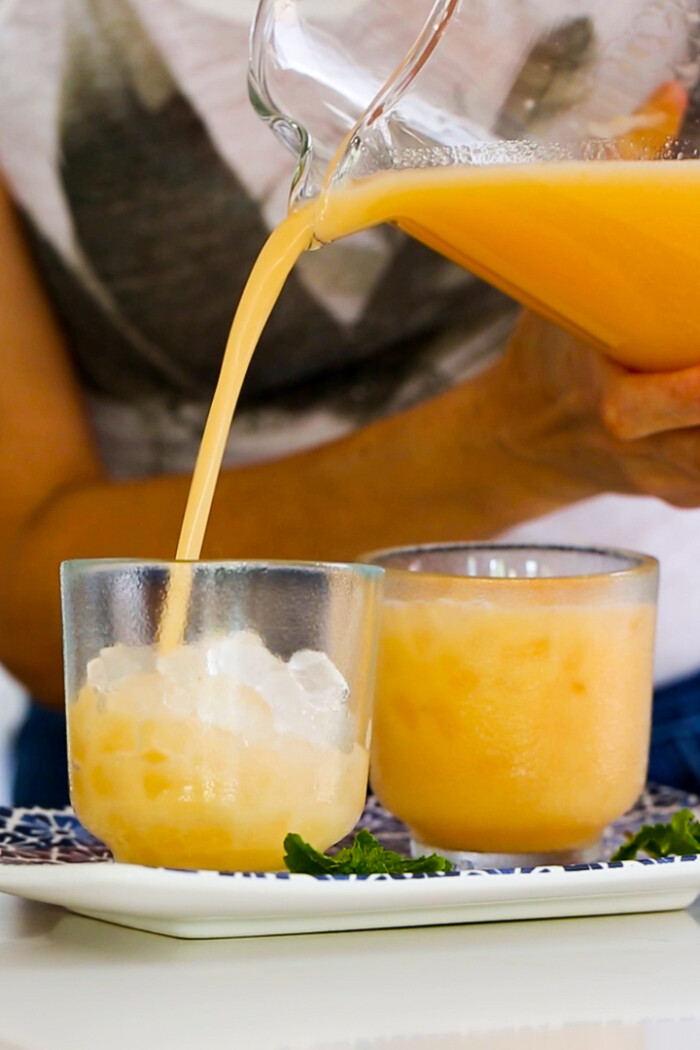 serving agua de melon into glasses with ice