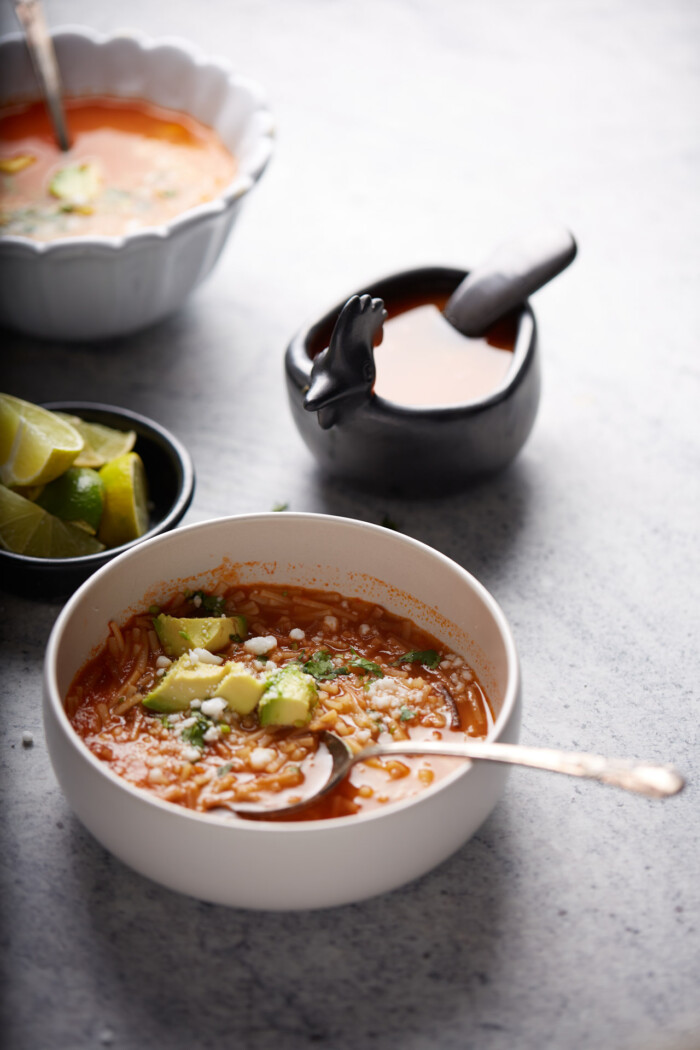 bowl of sopa de fideo with diced avocado and cilantro.