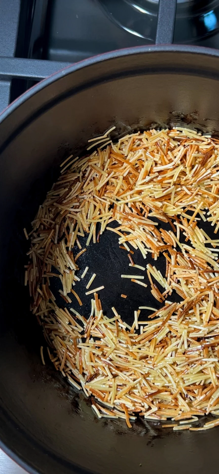 Fideo noodles toasted golden brown in a pot.