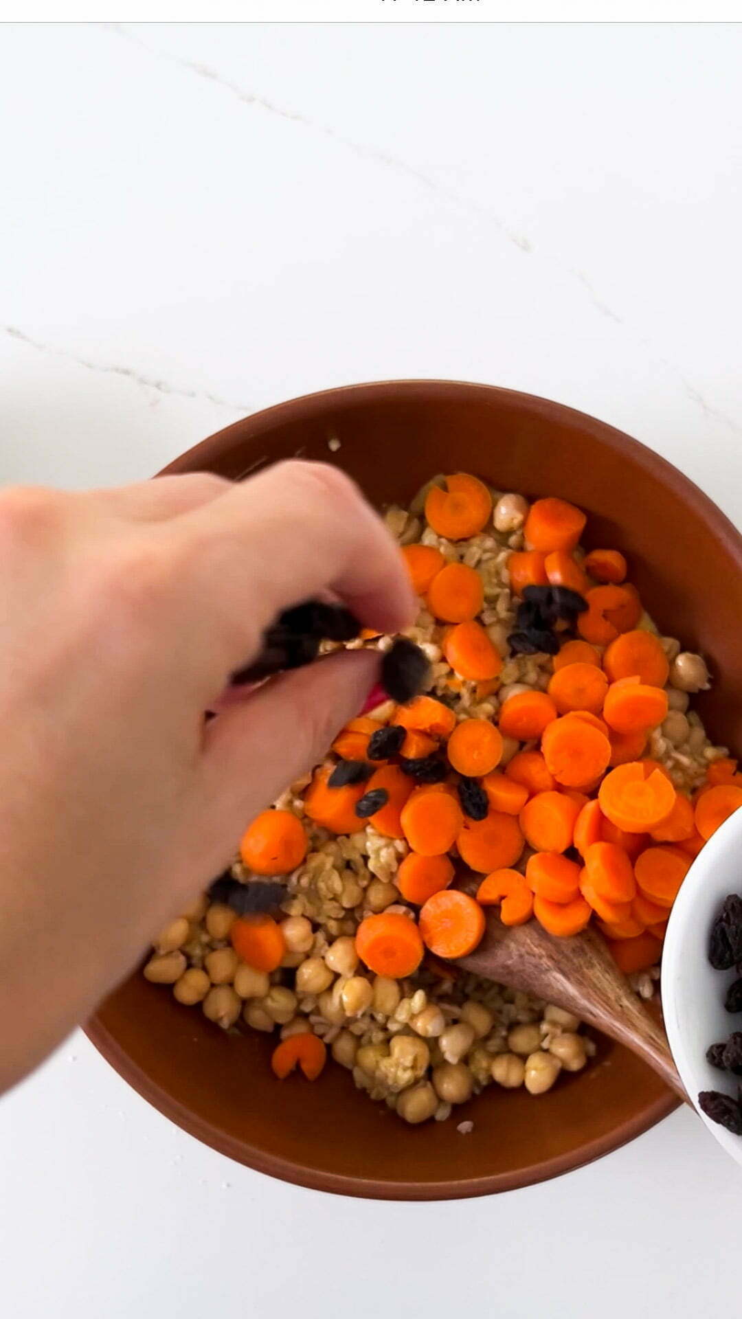 adding raisins and carrots to the curried chickpeas and farro