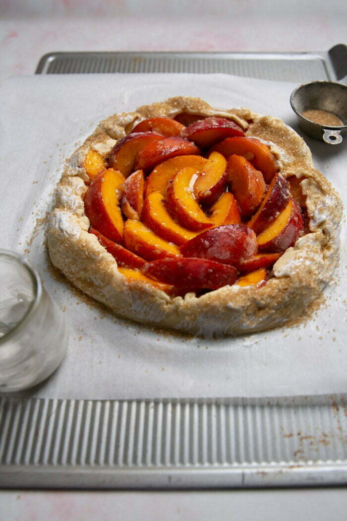 vegan rustic peach galette with sugar on the edges before baking