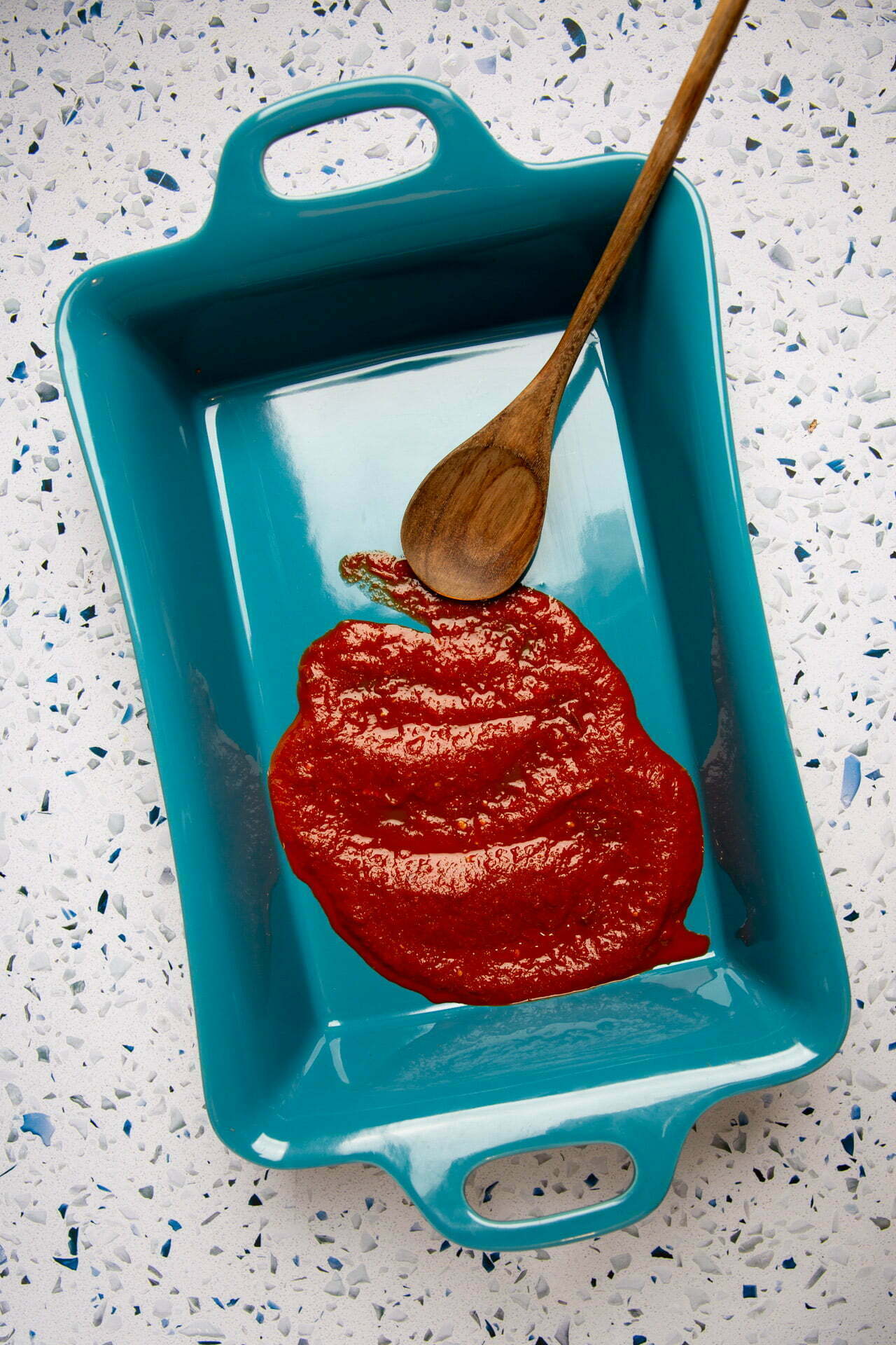 Vegan enchilada casserole topped with shredded cheese in a baking dish, ready to go in the oven