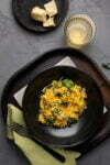 Risotto with pumpkin and sage on a black plate.