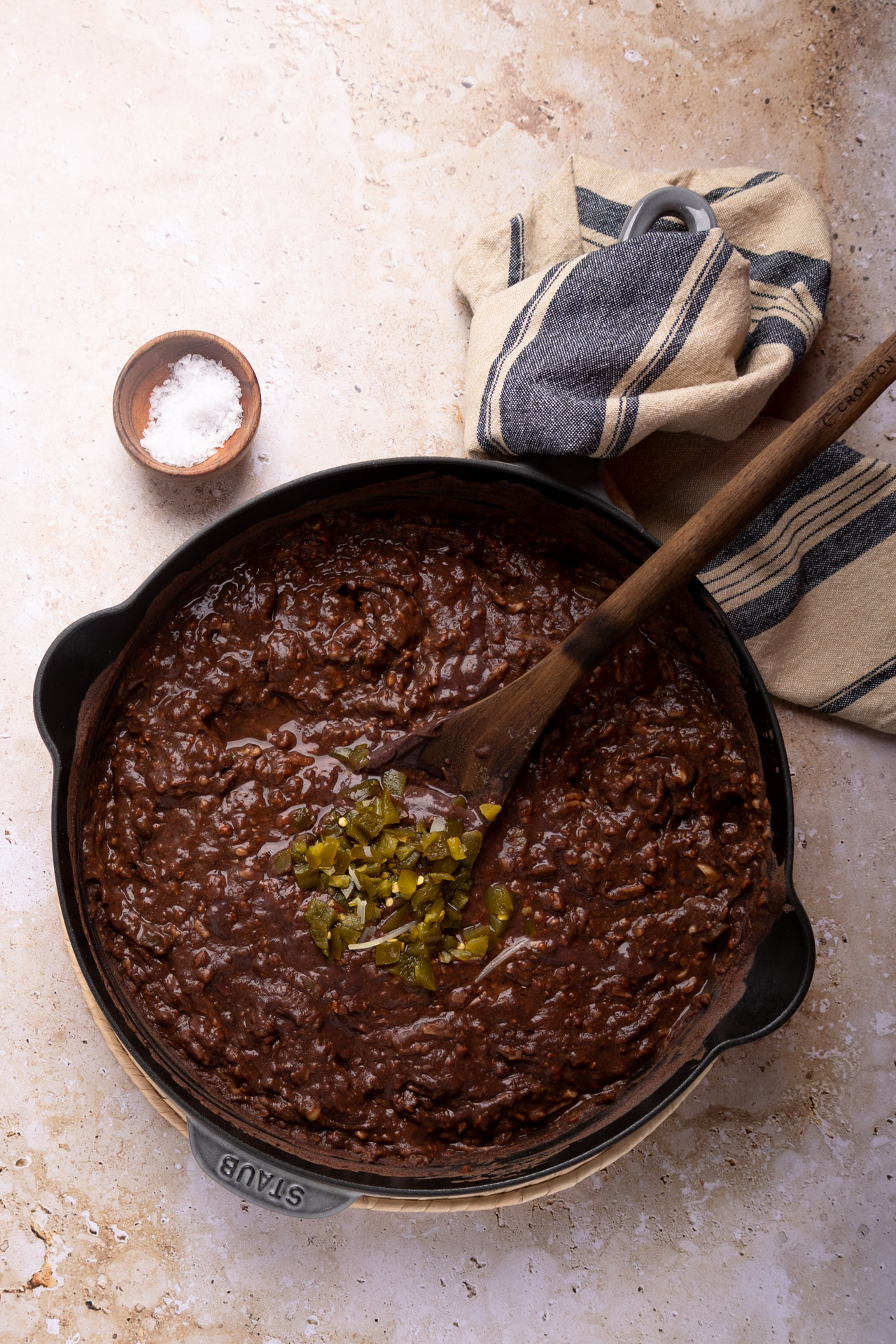 Frijoles puercos con jalape&ntilde;os picados en sart&eacute;n de hierro fundido con cuchara de madera