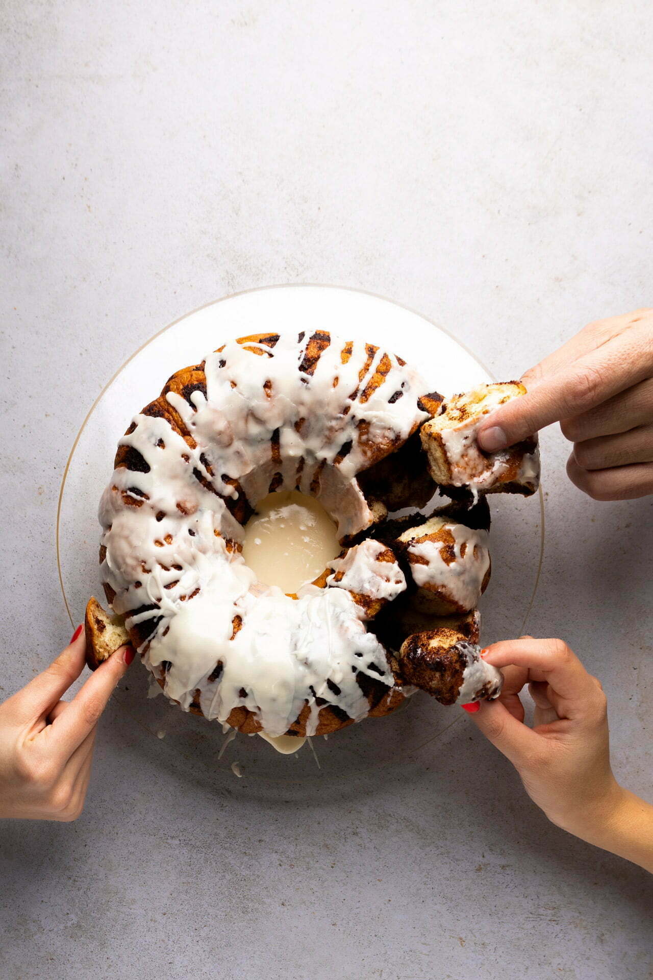 Two hands holding a vegan bundt cake on a plate.