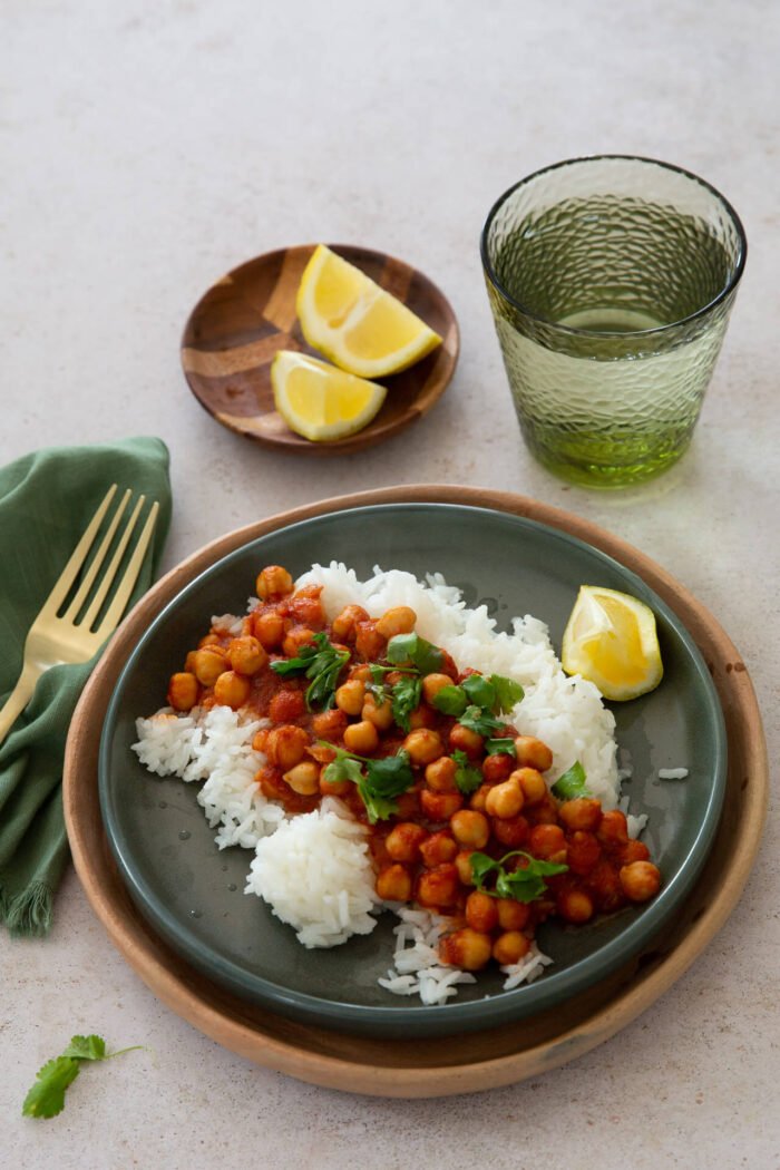 Chana masala over white rice with fresh cilantro and a squeezed lime on the side.