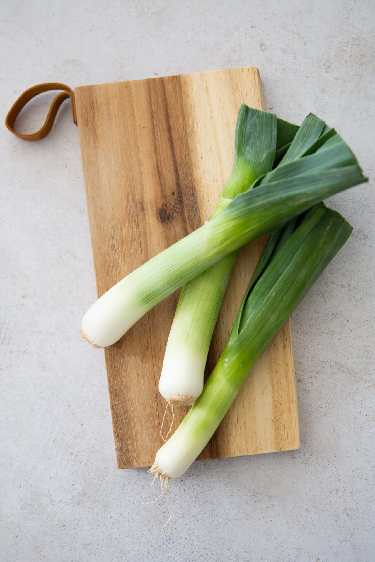 Leeks on a wooden cutting board, All About Leeks.