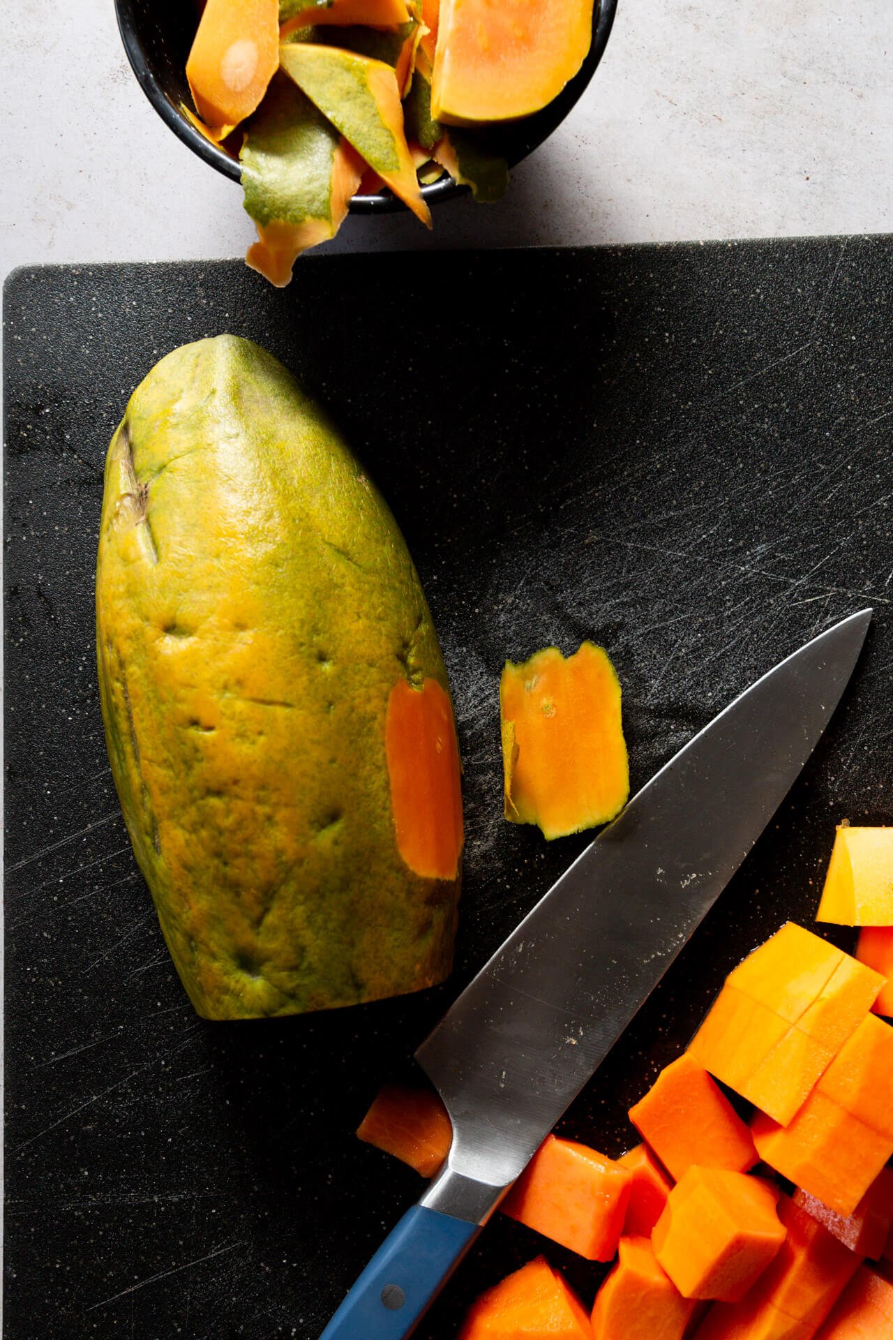 peeling a papaya on a black cutting board