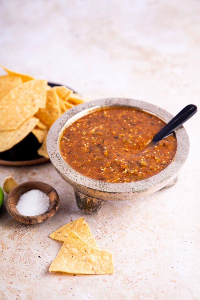 Tomatillo chipotle salasa in a silver saucer and chips on the side
