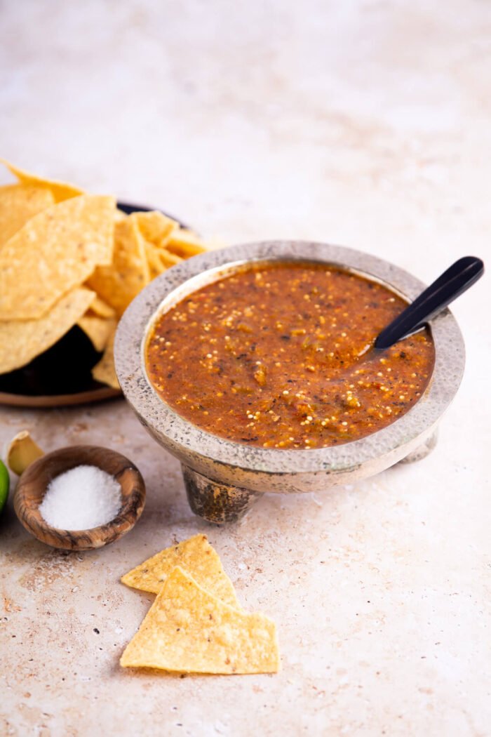 Tomatillo chipotle salasa in a  silver saucer and chips on the side