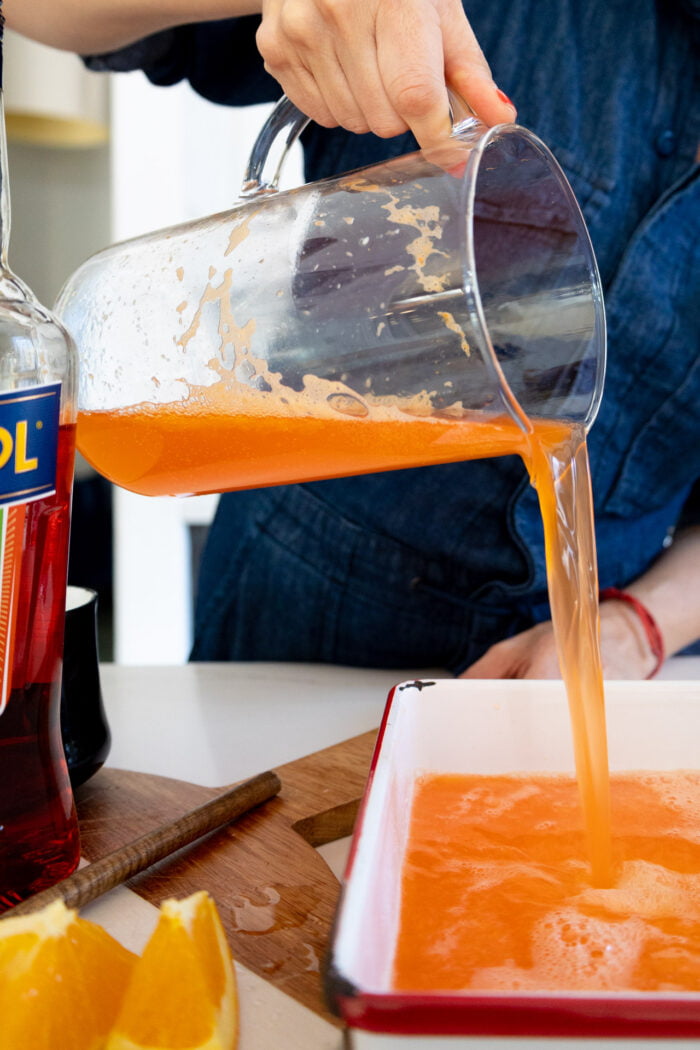 Pouring the aperol spritz granita mix into a dish