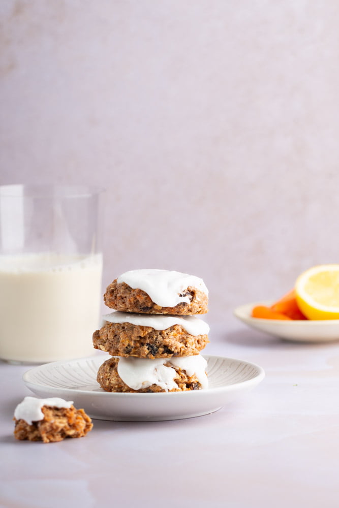 carrot breakfast cookies, one on top of the other with a glass of milk on the bottom