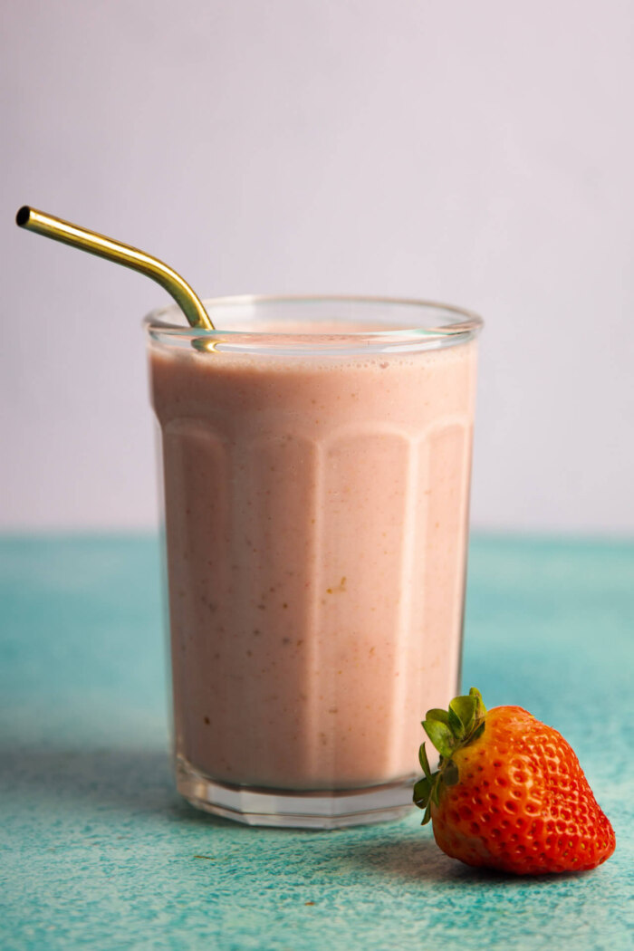 strawberry smoothie in a glass with a golden straw