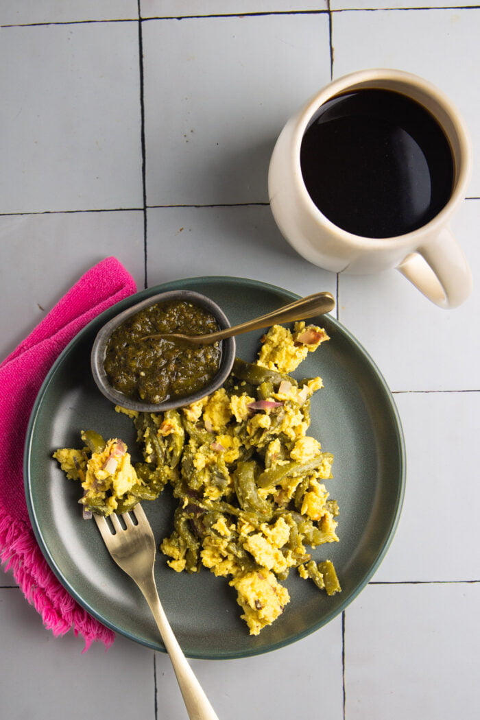 Nopales con huevo on a dish next to a  cup of coffee and some salsa