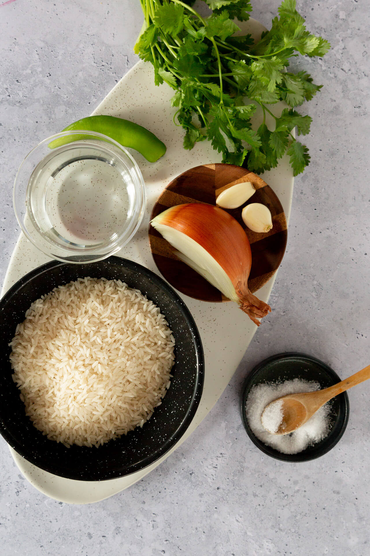 dry rice, plus water, onion and garlic cloves. A serrano chile and cilantro on the side.