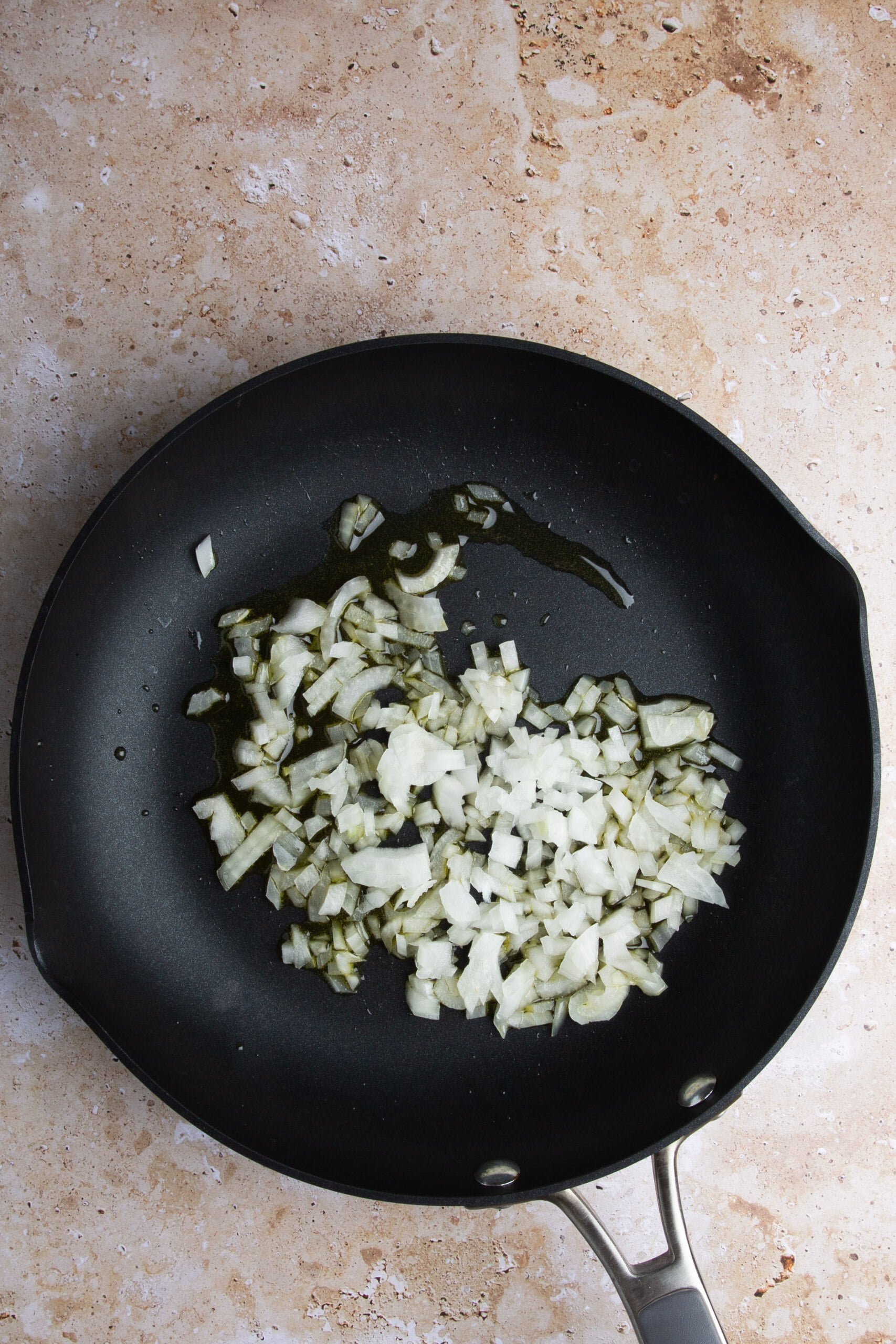 Chopped onion frying in olive oil in a skillet