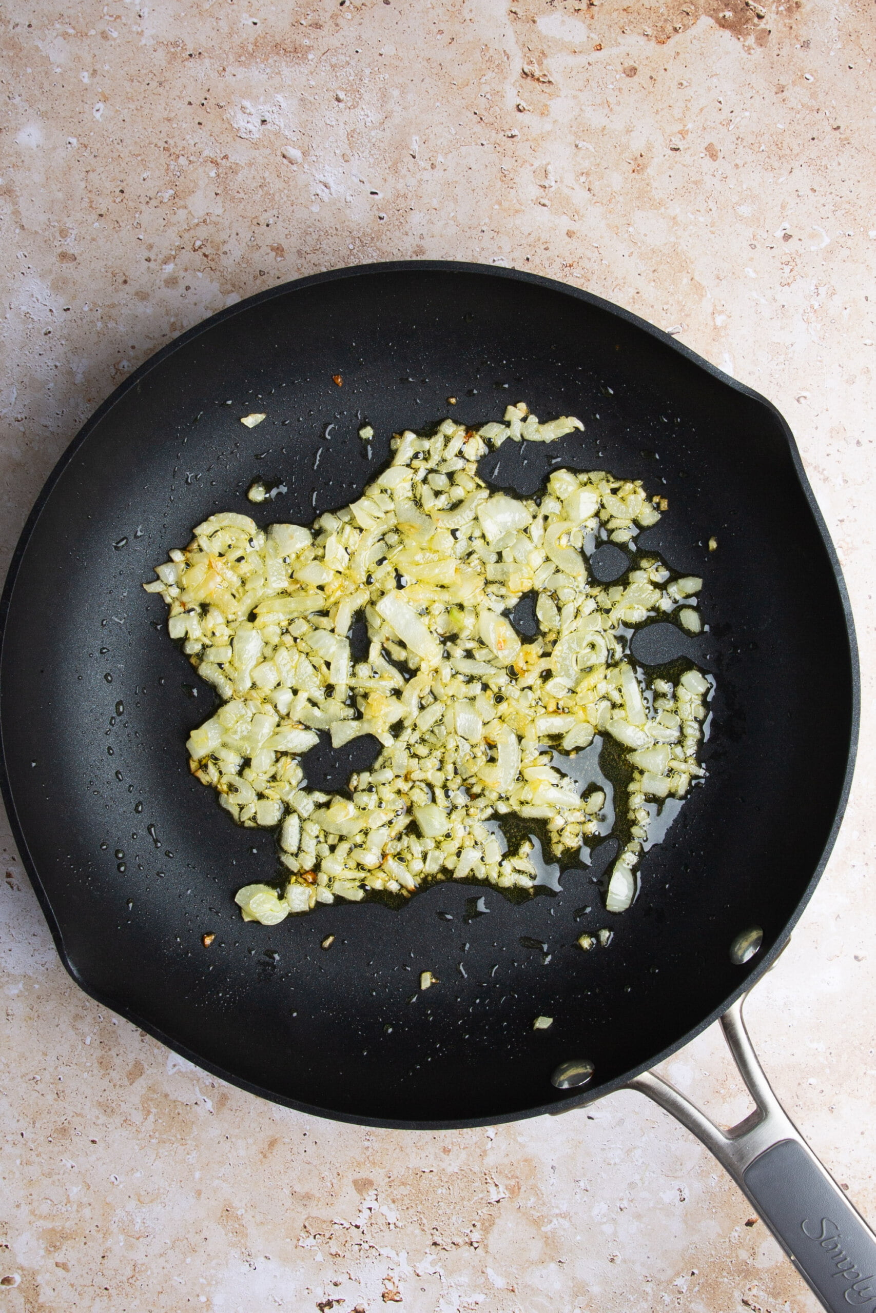 Beans being added to a skillet with fried onion