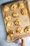 A person holding cookies on a baking sheet.