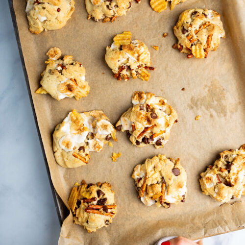 A person holding cookies on a baking sheet.