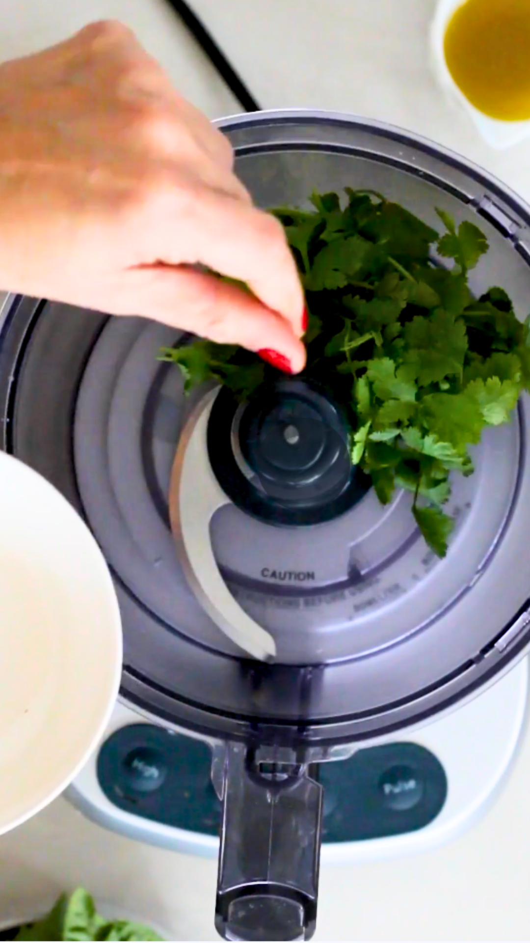 A person using a food processor to make vegan pesto.