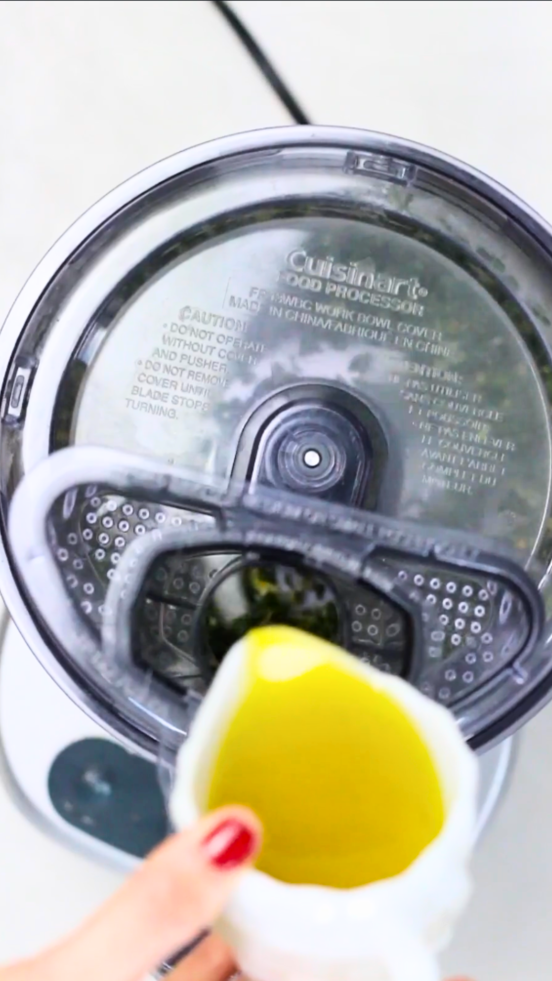 Preparing vegan pesto by pouring olive oil into a blender.