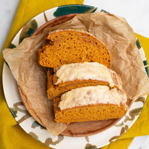 A slice of vegan pumpkin bread sprinkled with spices, served on a plate.