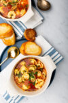 Two bowls of healthy soup with bread on a table.