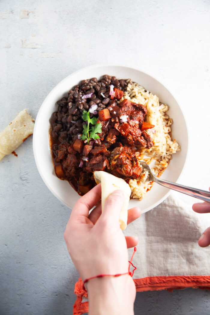 A person enjoying a bowl of black beans and rice.