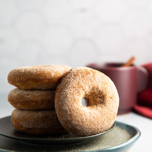 A stack of vegan apple cider donuts on a plate.