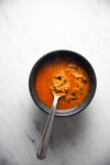 A bowl of Sopa de Fideo soup with a spoon in it.