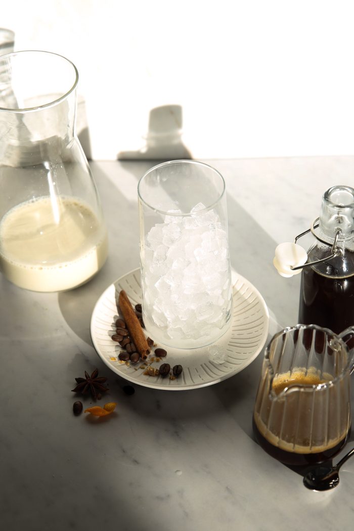 A cup of iced Café de Olla with cinnamon on a plate.