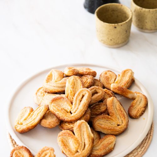 A plate of vegan cookies on a table next to a cup of tea.