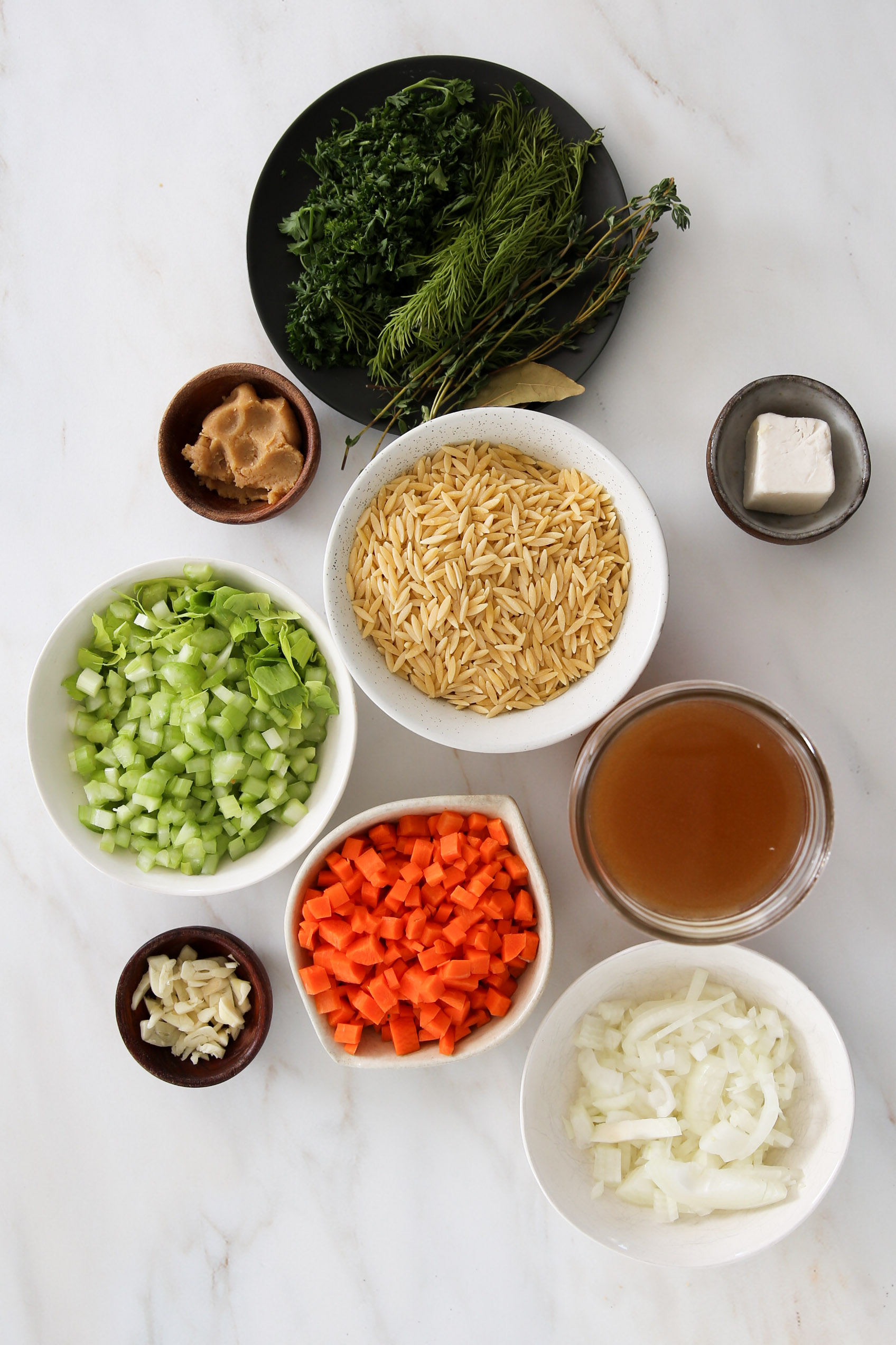 A bowl of vegan noodle soup with carrots, onions, and other ingredients.