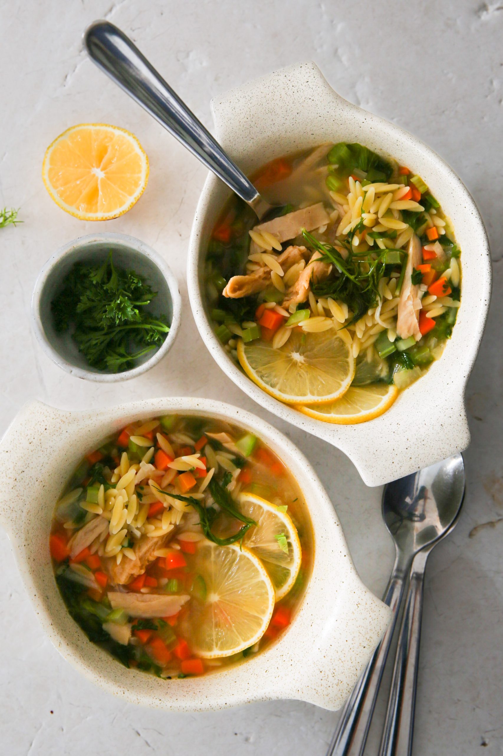 Two bowls of chicken noodle soup with lemon.