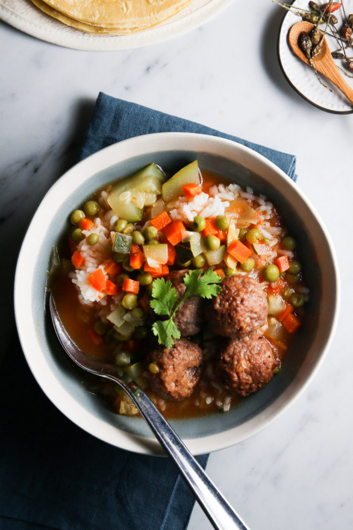 A bowl of Vegan soup with meatballs and vegetables.