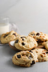 Chocolate chip cookies on a plate next to a glass of milk.