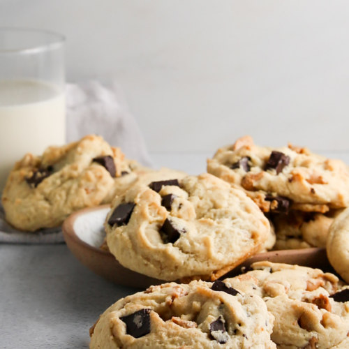 Chocolate chip cookies on a plate next to a glass of milk.